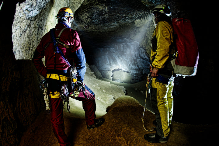 men standing in cave using headlamps to illuminate it