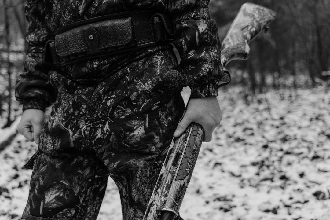 hunter carrying shotgun walking through a snowy field