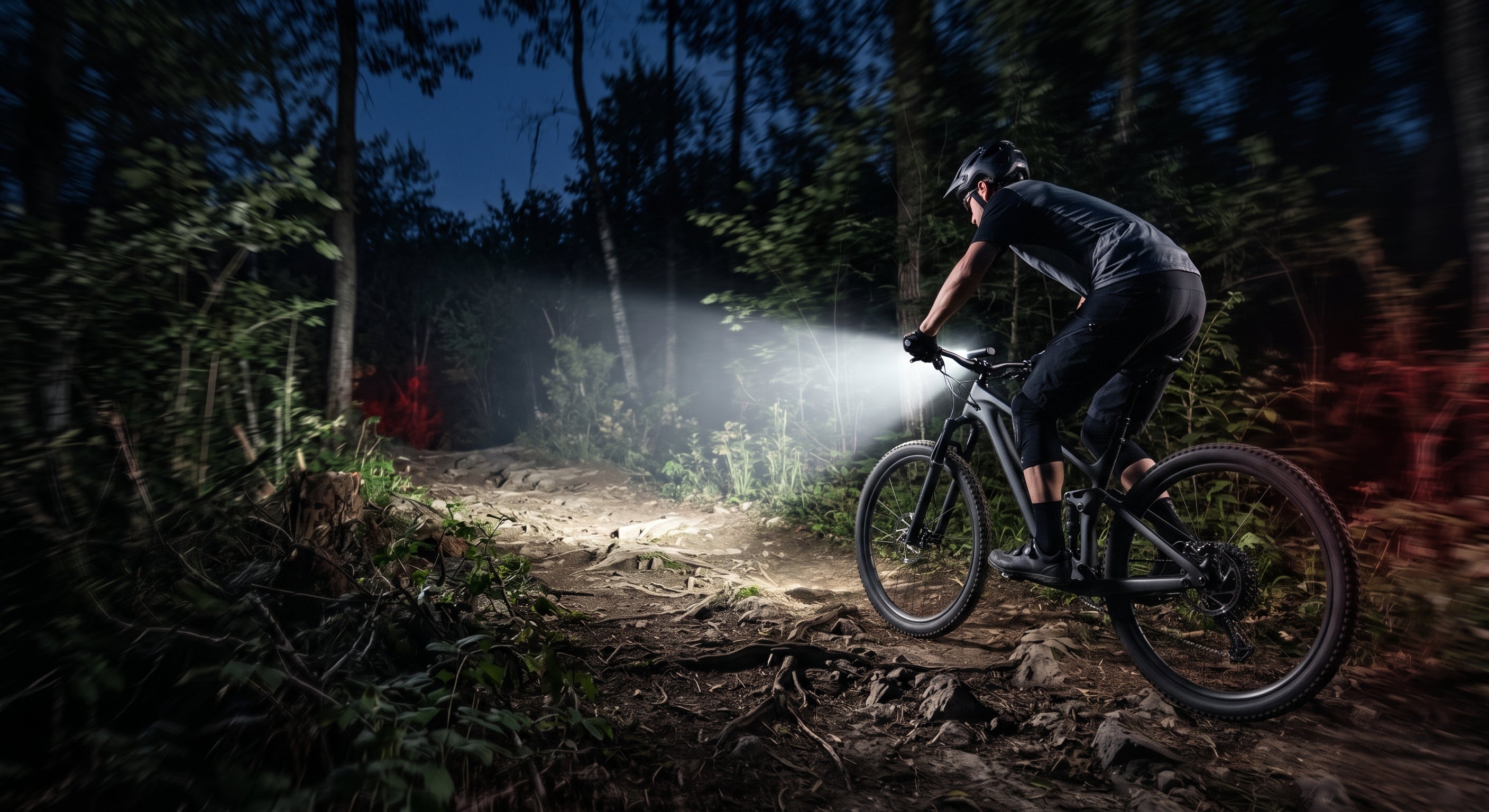 mountain biker riding through the woods with a bike light shining ahead