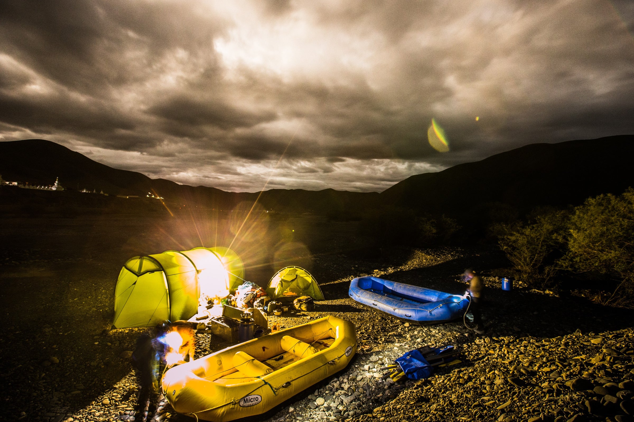camping on a riverbank with a lantern