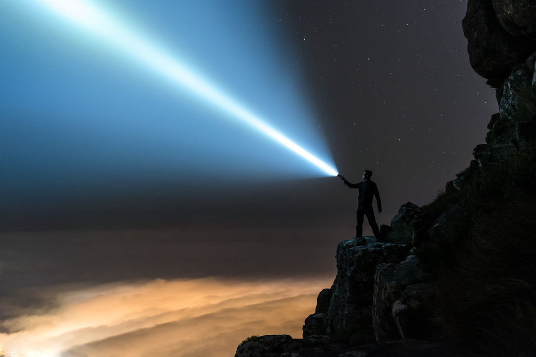 man using a flashlight on a cliff
