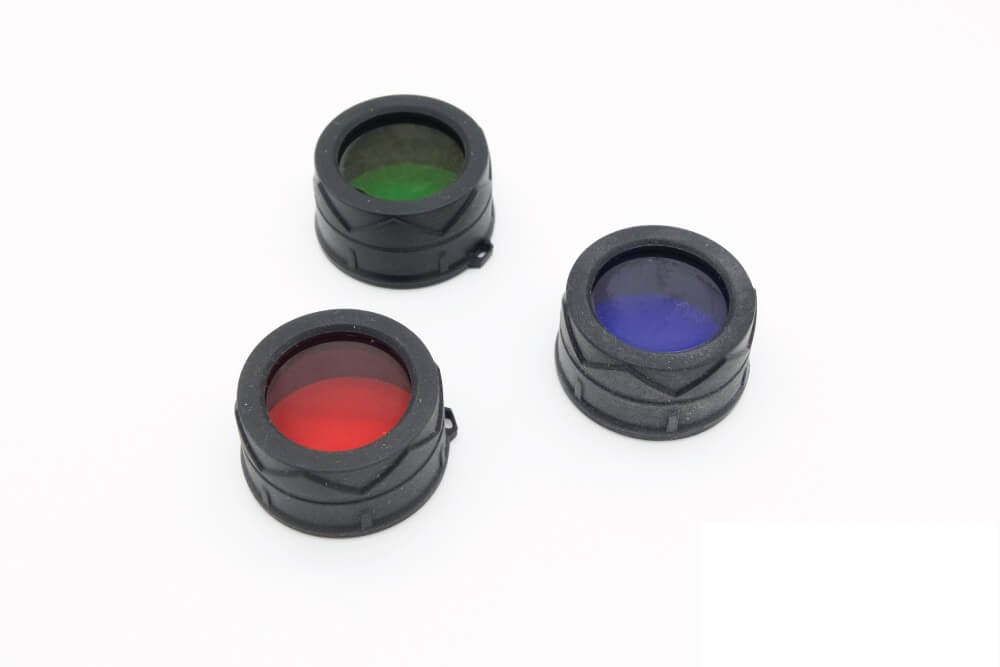Three colored filters (red, green, and blue) for flashlights, placed next to each other on a white surface.