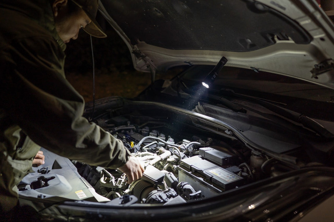 Person working under the hood of a car using the magnetic tail cap of the Fenix C7 Pro Quick-Charging Work Flashlight 