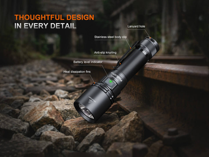 Black Fenix C7 V2 flashlight on rocks with features highlighted, outdoors.