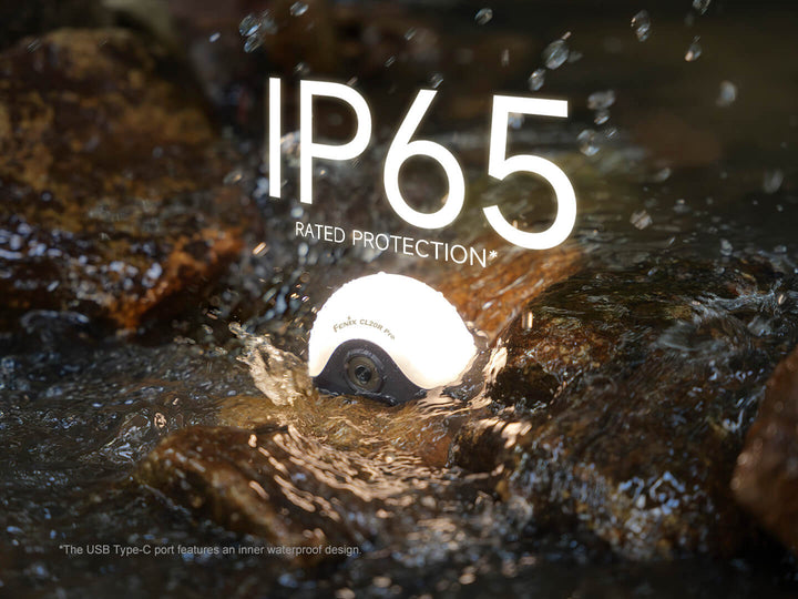 Fenix CL20R Pro camping lantern with IP65 rating submerged in water, surrounded by rocks.
