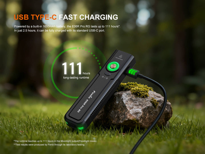 USB Type-C fast charging Fenix E06R Pro RG Green Laser Flashlight on a rock with grass and blurred natural background