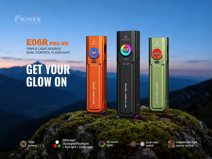Three Fenix E06R Pro RG Green Laser Flashlights on a rock with a mountainous background