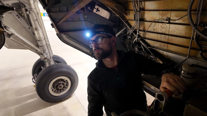 Person using a Fenix HM53R headlamp working under an airplane 