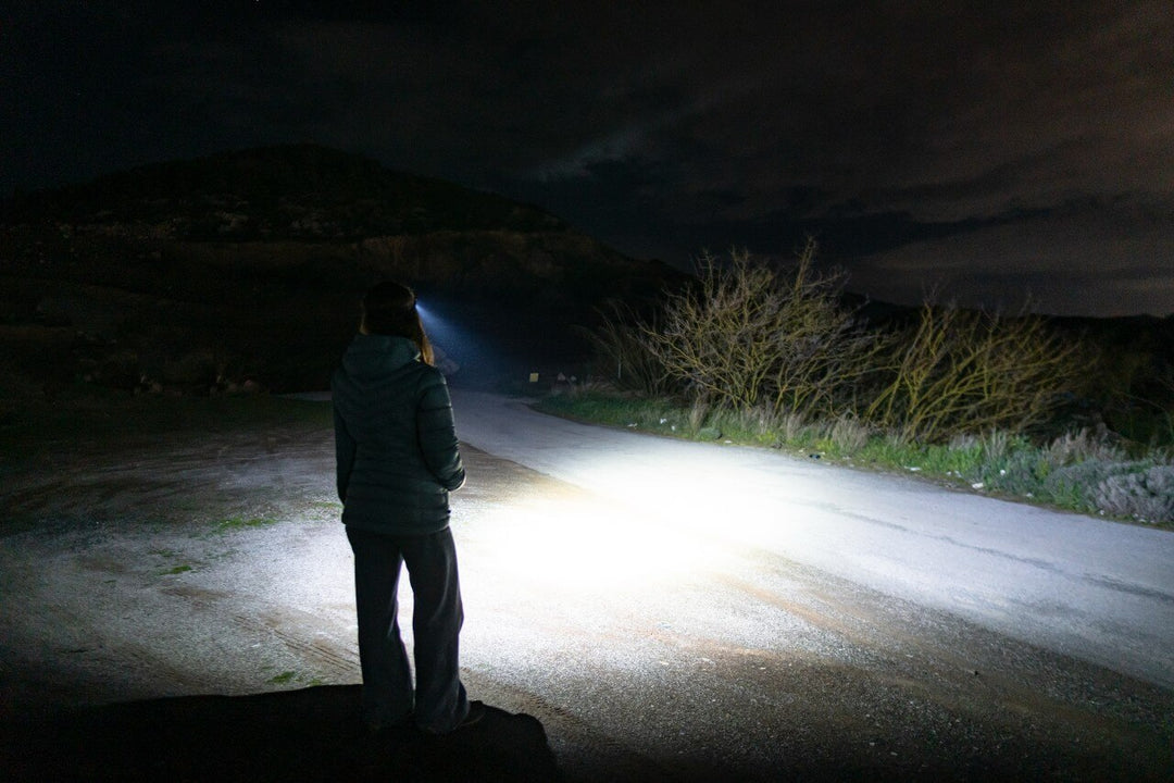 Person standing on a dark road using a Fenix HM53R headlamp 
