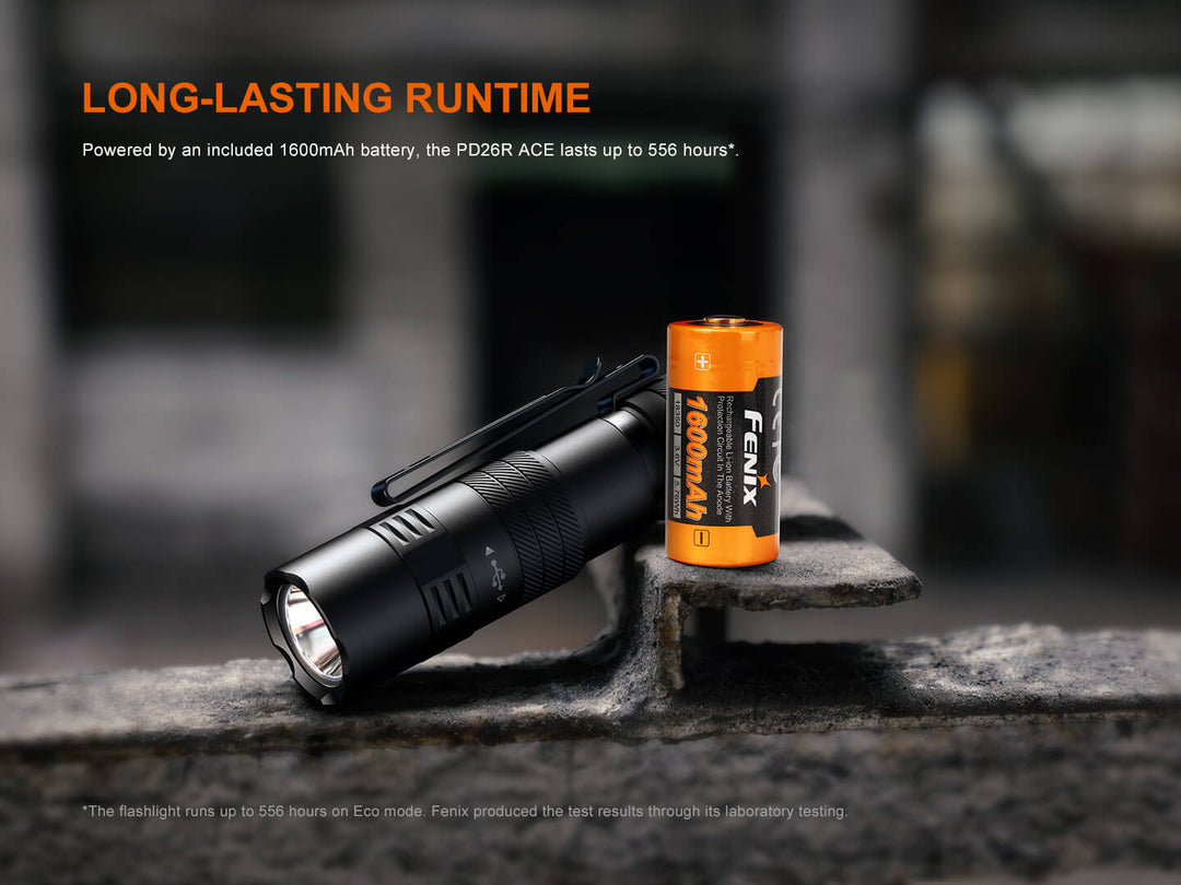 Fenix PD26R ACE Customizable Compact Flashlight and battery on a metal surface with text about long-lasting runtime.