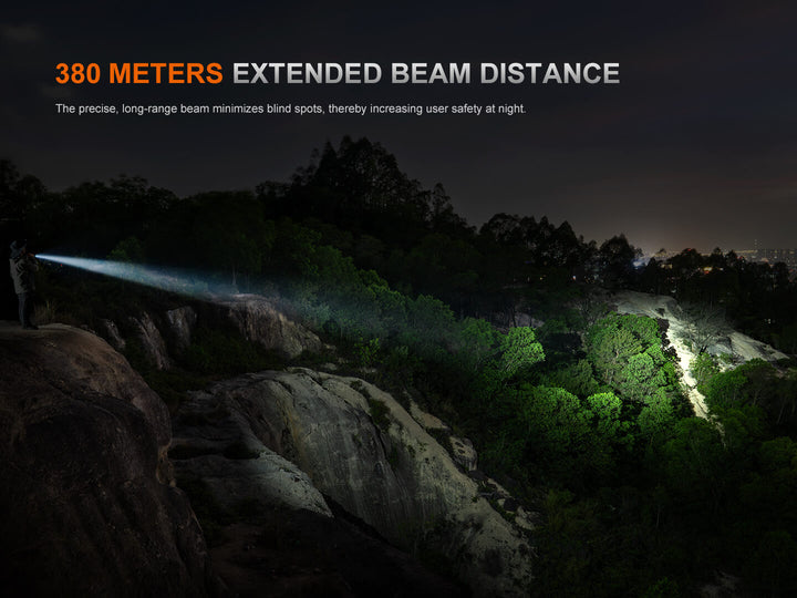 Fenix PD35R ACE Customizable Flashlight illuminating a forested area at night with text about extended beam distance.