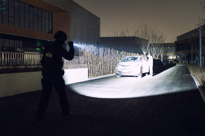 Person using a Fenix TK15R adaptive flashlight  to inspect a car in a dark outdoor setting