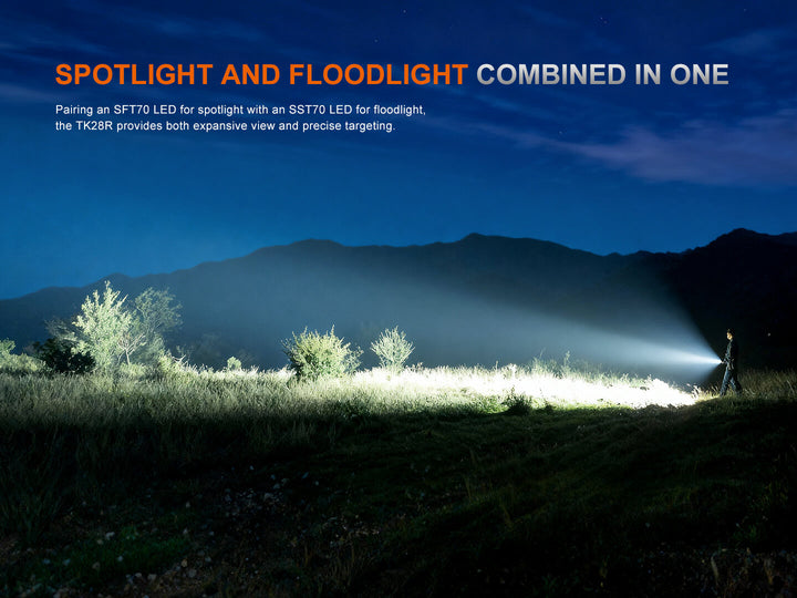 Fenix TK28R Flashlight projecting spotlight and floodlight onto a landscape with mountains and trees.