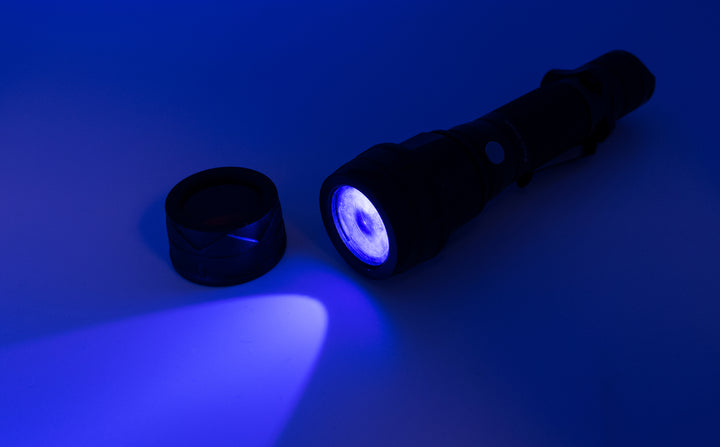 A flashlight turned on with a blue 34mm filter attached