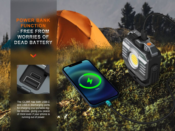 The Fenix CL28R multifunctional outdoor lantern on a mossy stone being used to recharge a cell phone