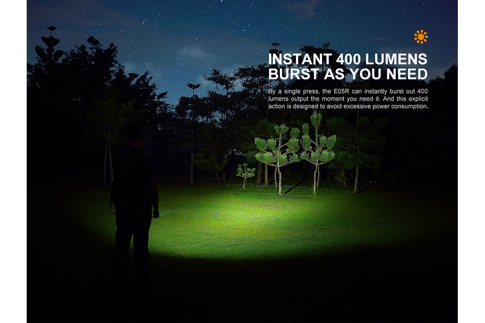 Fenix E05R Mini Keychain LED Flashlight used to light up a field with trees