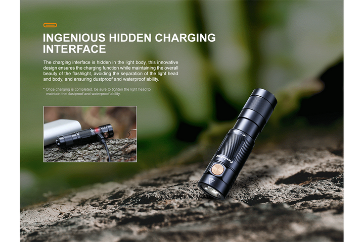 Fenix E09R rechargeable flashlight plugged in via hidden charging port, lying on a log in the woods